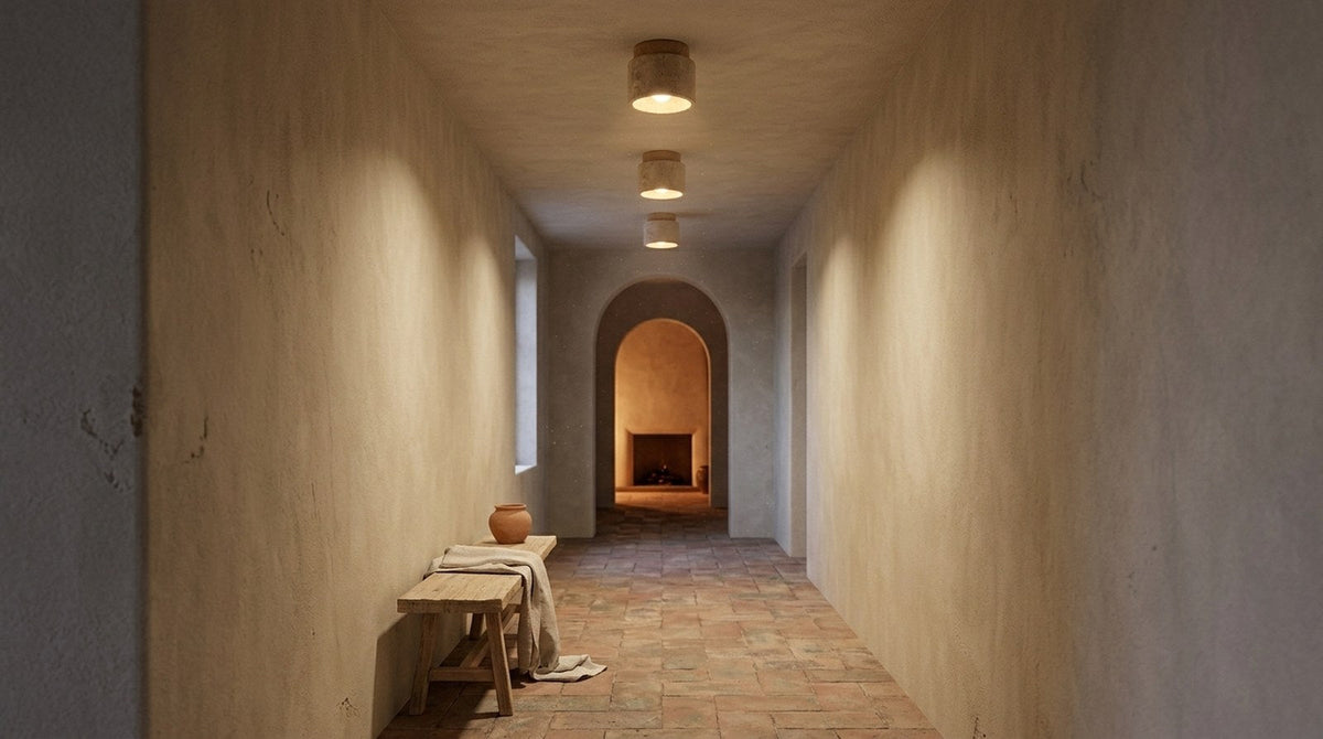 Pasillo con arco y suelo de terracota iluminado por plafones cilíndricos de travertino